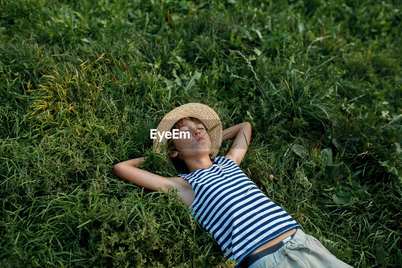 Teenage boy making face while lying on grass outdoors