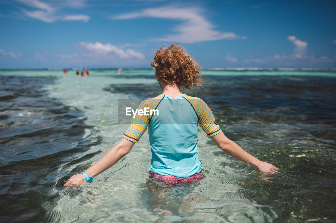 Rear view of woman in sea against sky