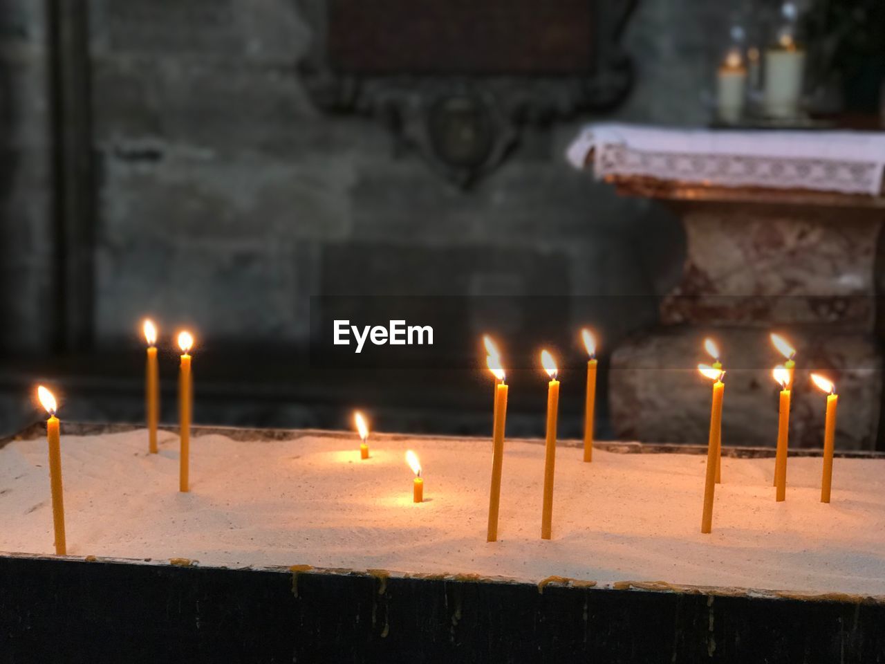 CLOSE-UP OF ILLUMINATED CANDLES ON TEMPLE