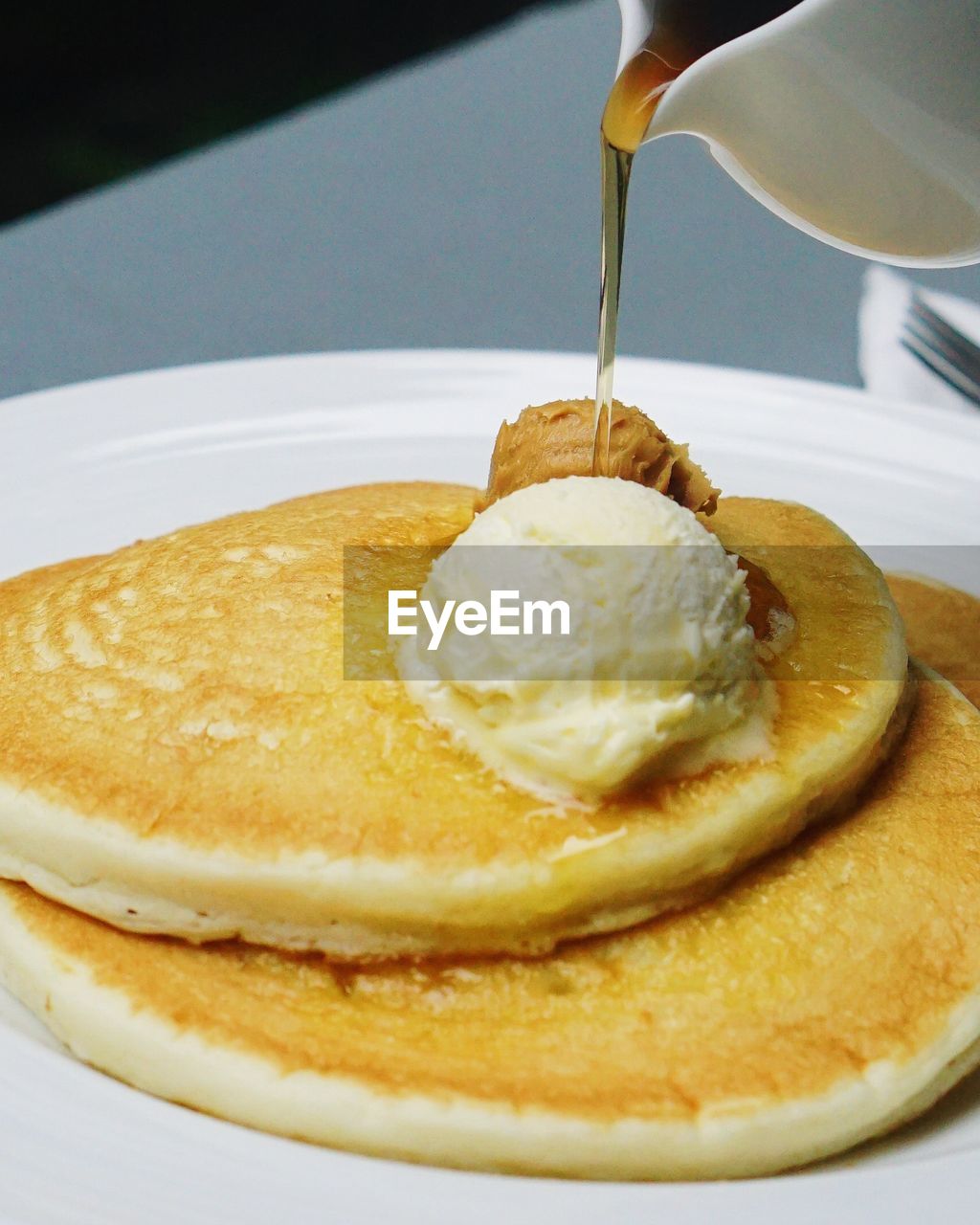 Syrup pouring on pancakes in plate