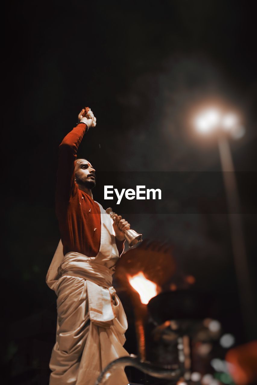 Low angle view of man in traditional clothing during event in city at night