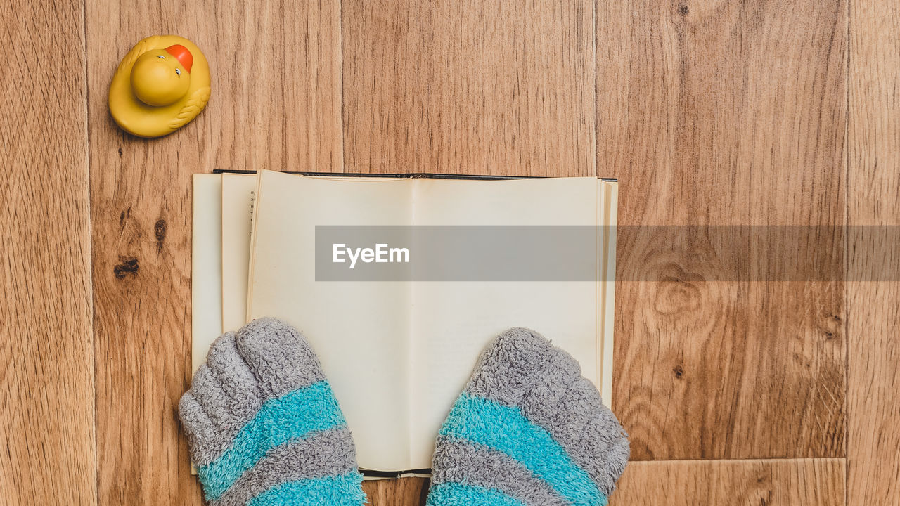 Striped socks with toes against a background of a book, a wooden floor, and a rubber duck.