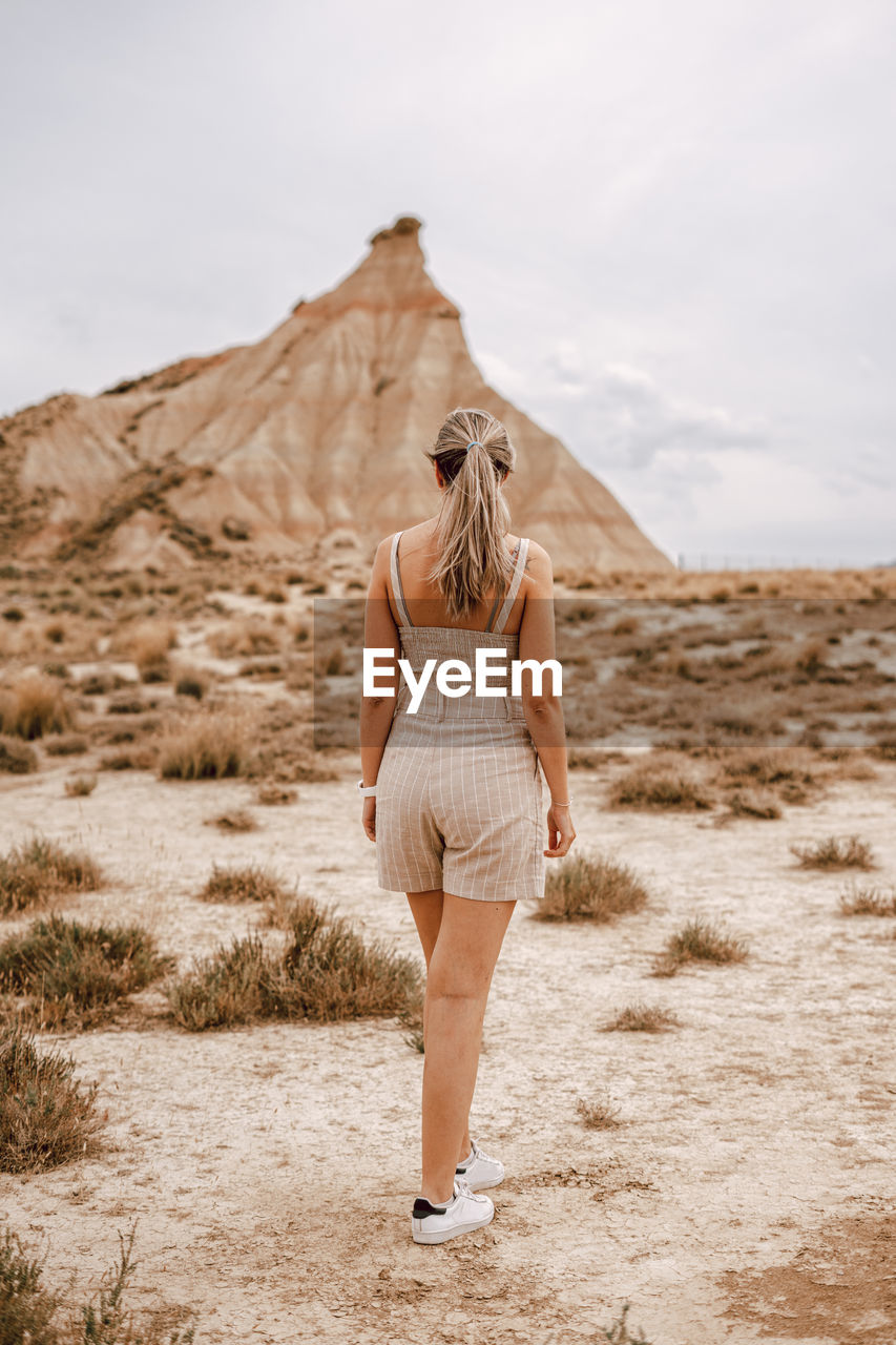 Full length rear view of woman standing on field against sky