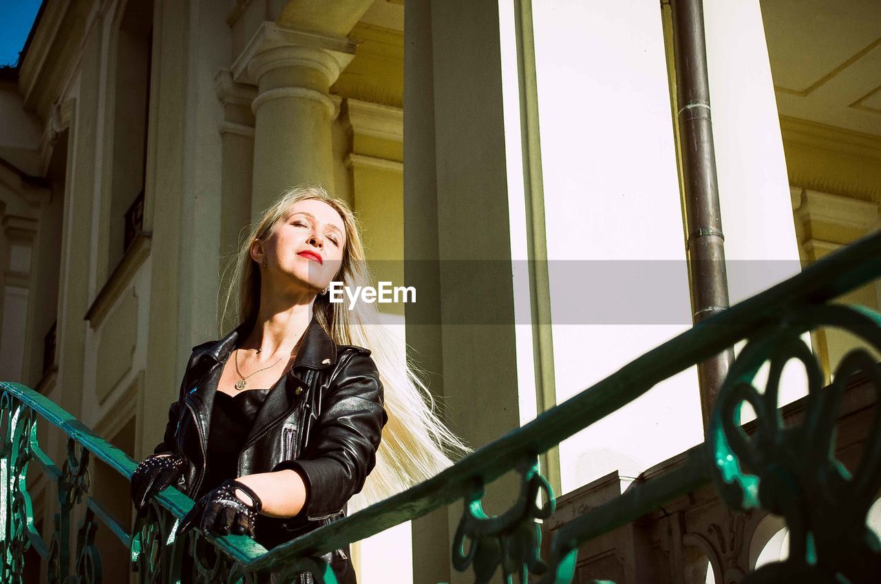 Full length portrait of woman standing against railing