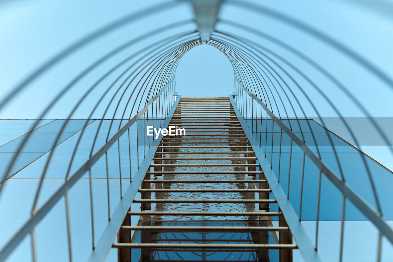 Fire escape staircase. long metal staircase on blue glass facade of building. emergency fire exit