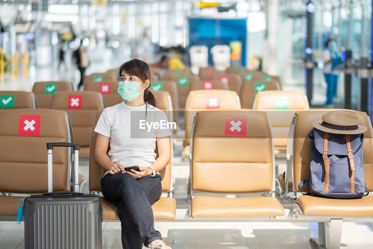 Full length of woman sitting on seat in airport