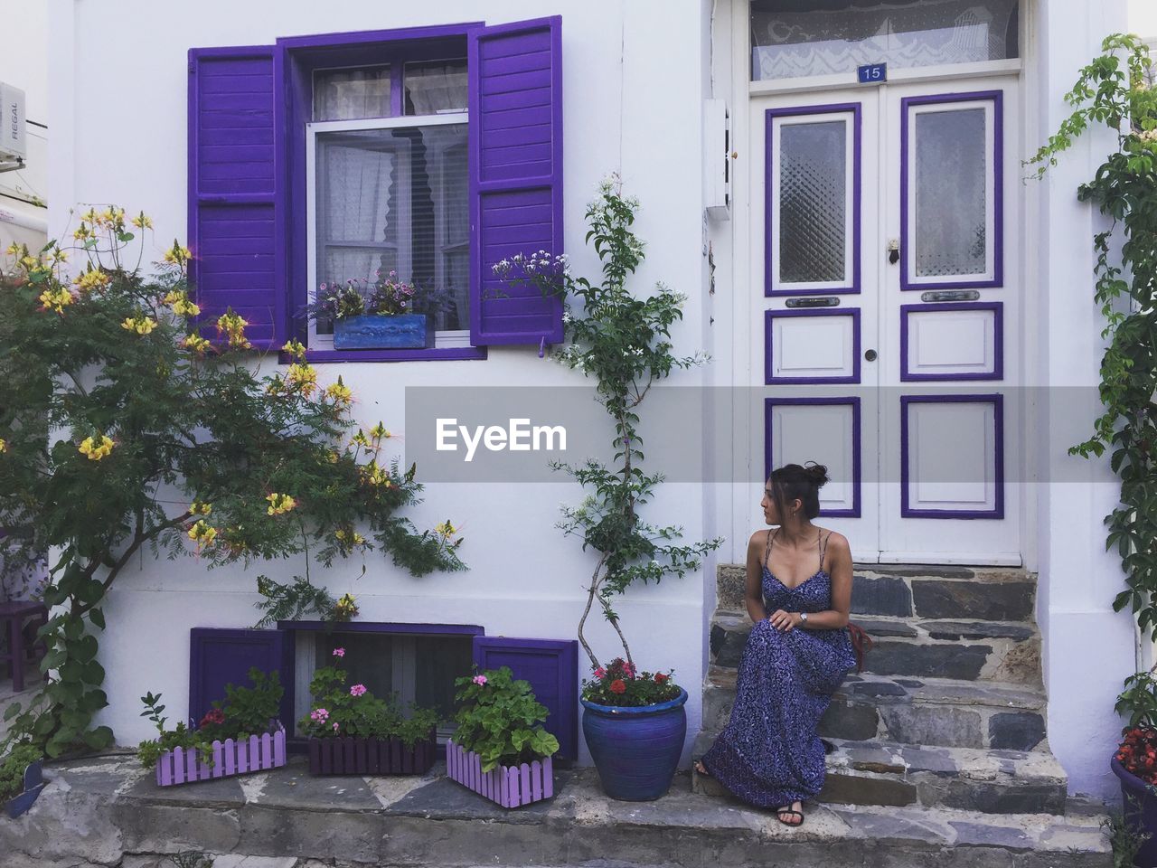 WOMAN STANDING BY POTTED PLANTS OUTSIDE HOUSE