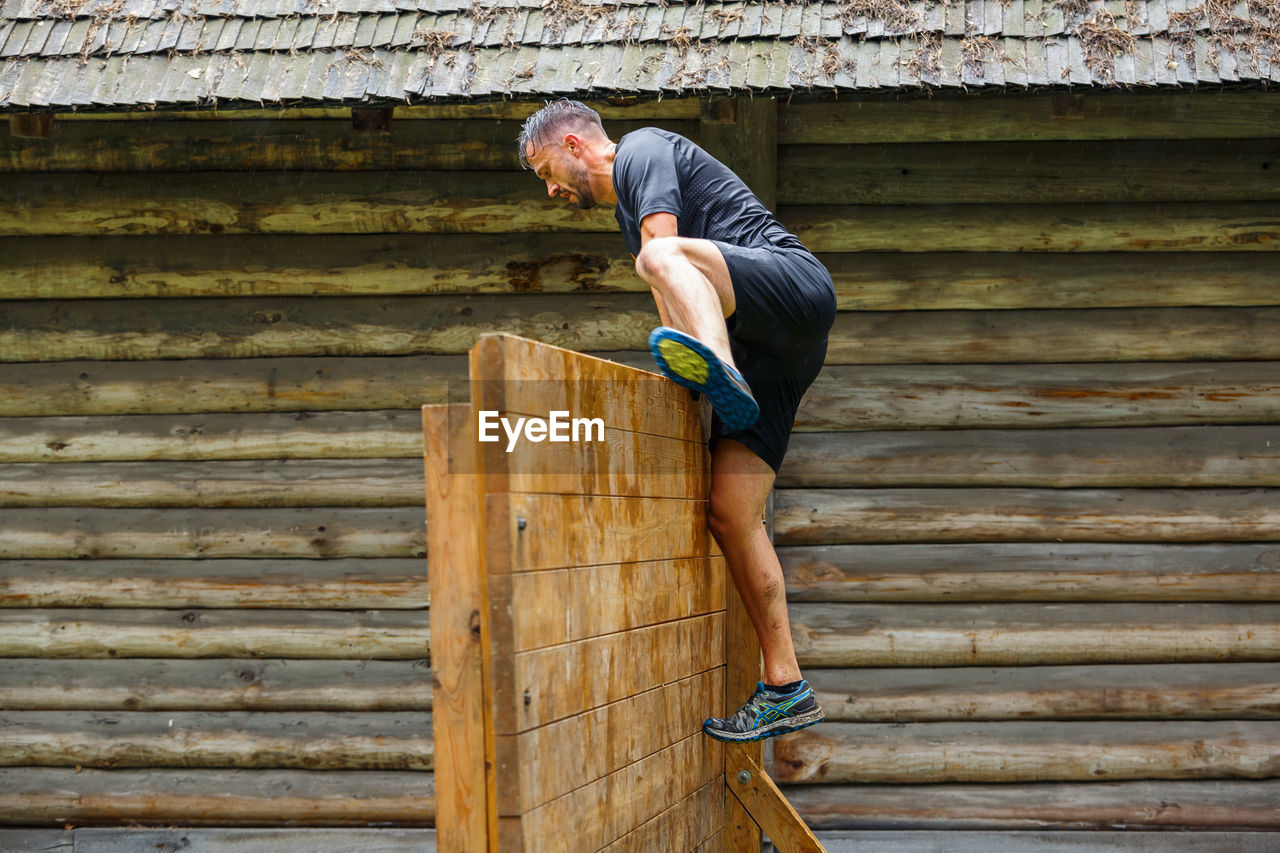 MAN STANDING ON WOODEN WALL