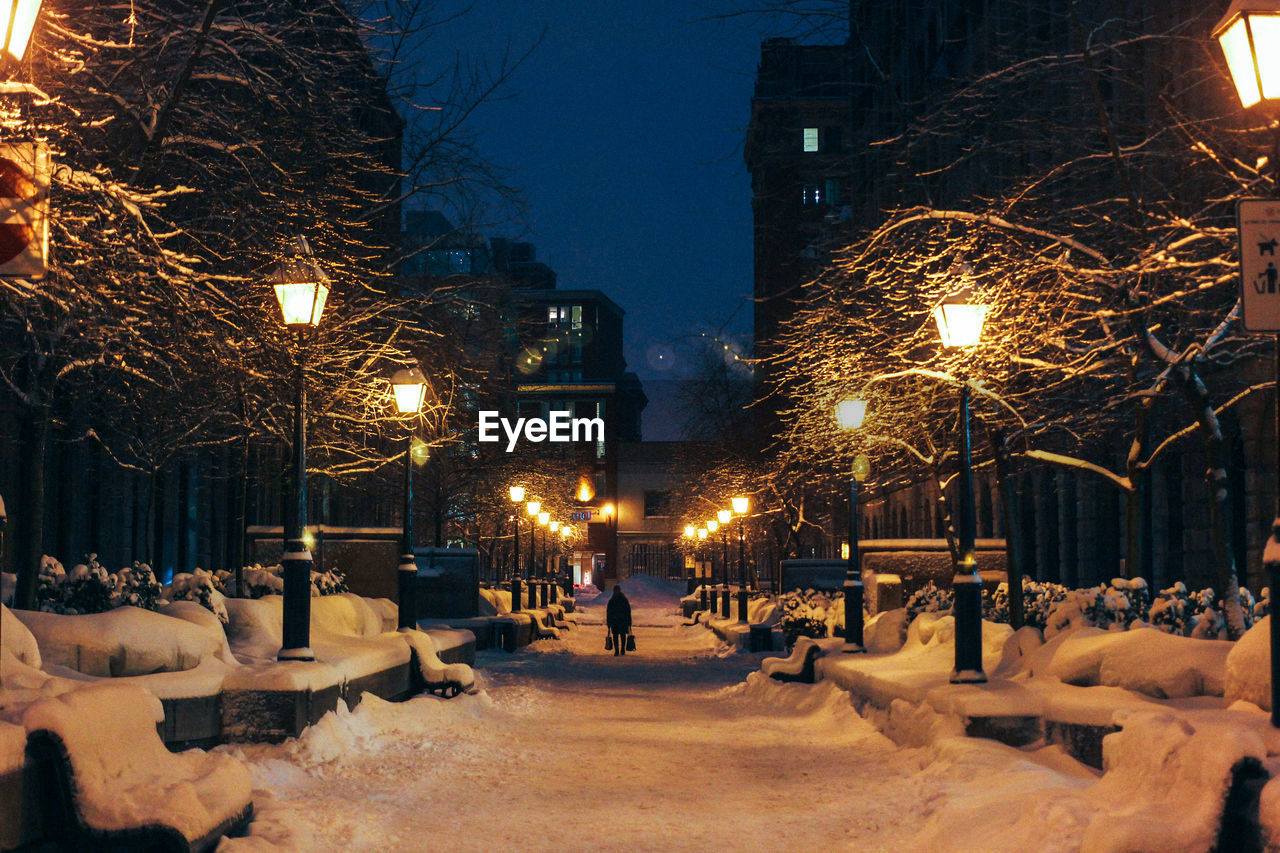 Illuminated snow covered walkway at night