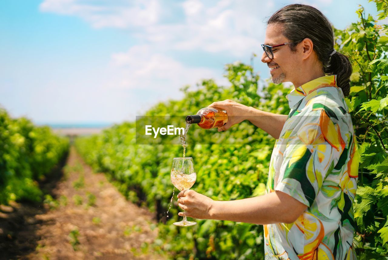 Man pouring wine in glass in vineyard