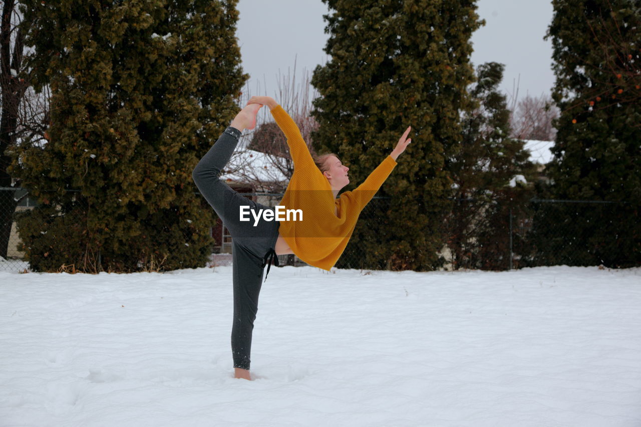 Young woman exercising on snow covered field