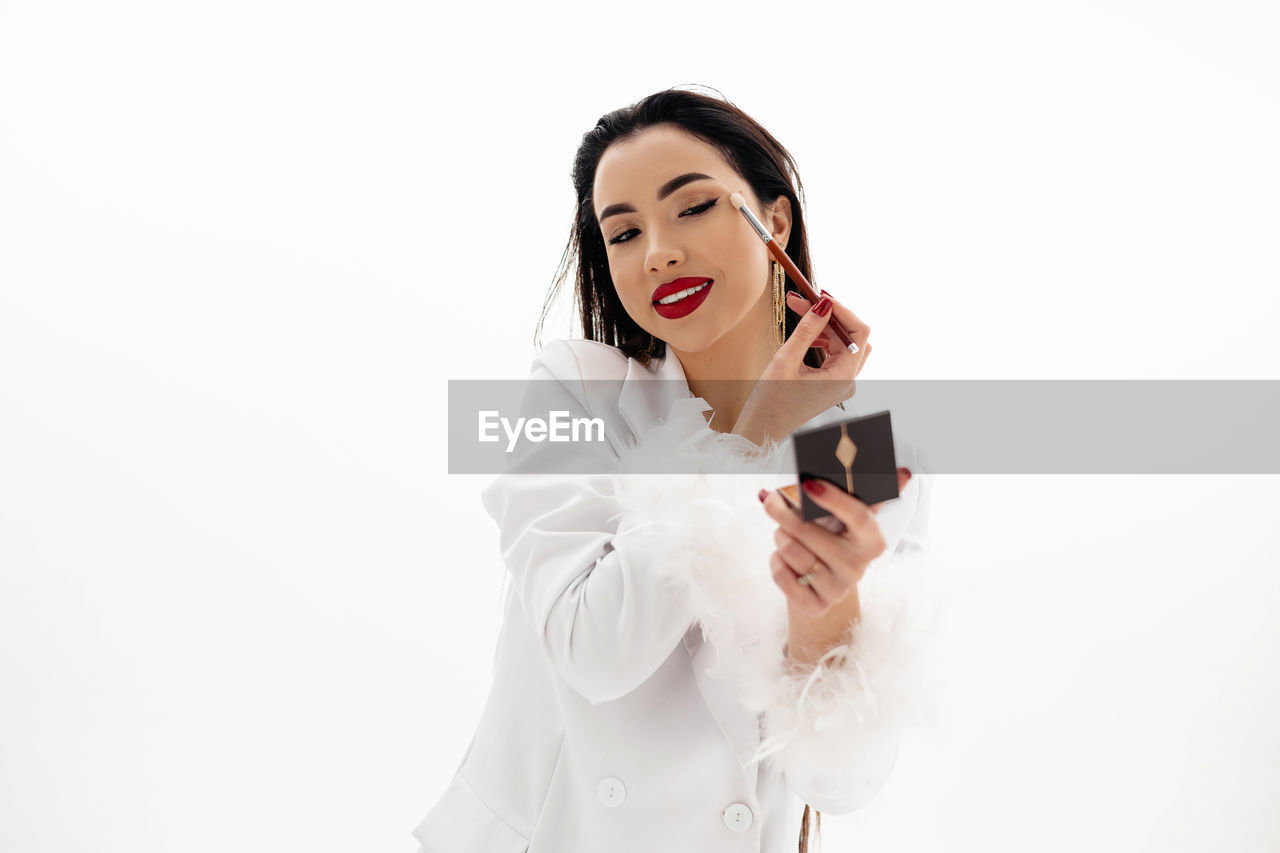 Portrait of a beautiful girl applying a makeup on a white background