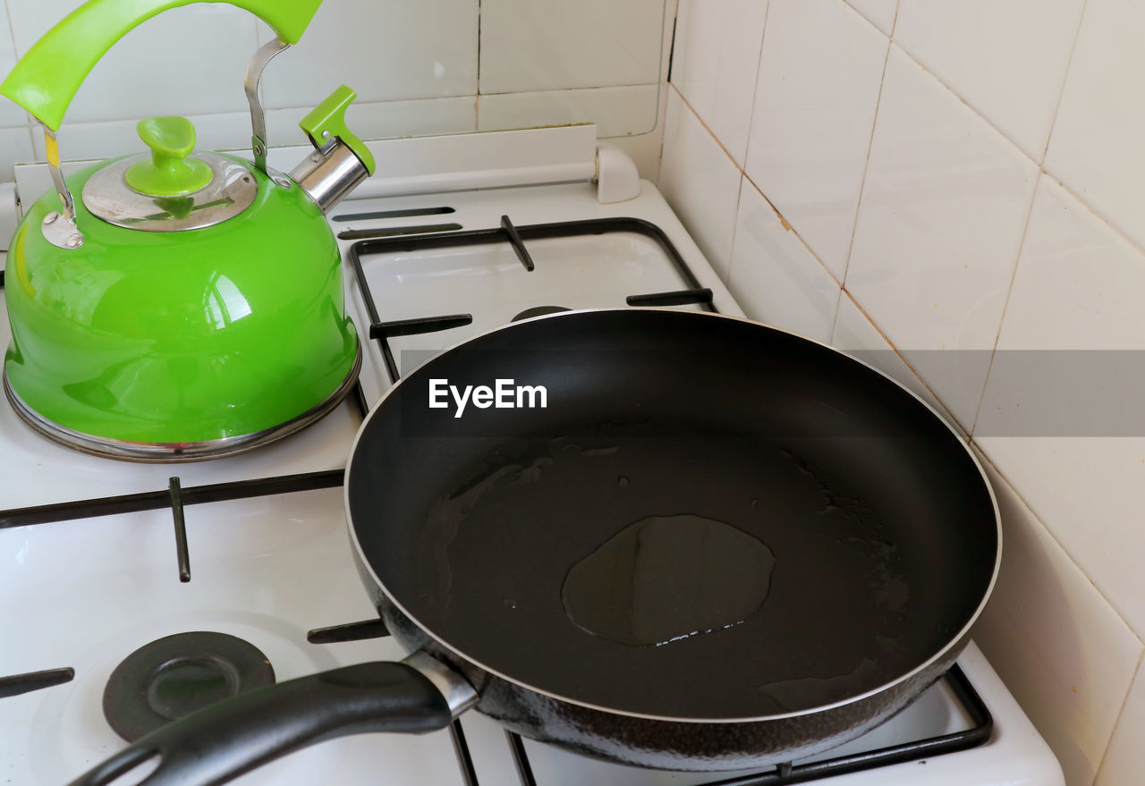 Fry pan with heated olive oil on the stove with a kettle in background