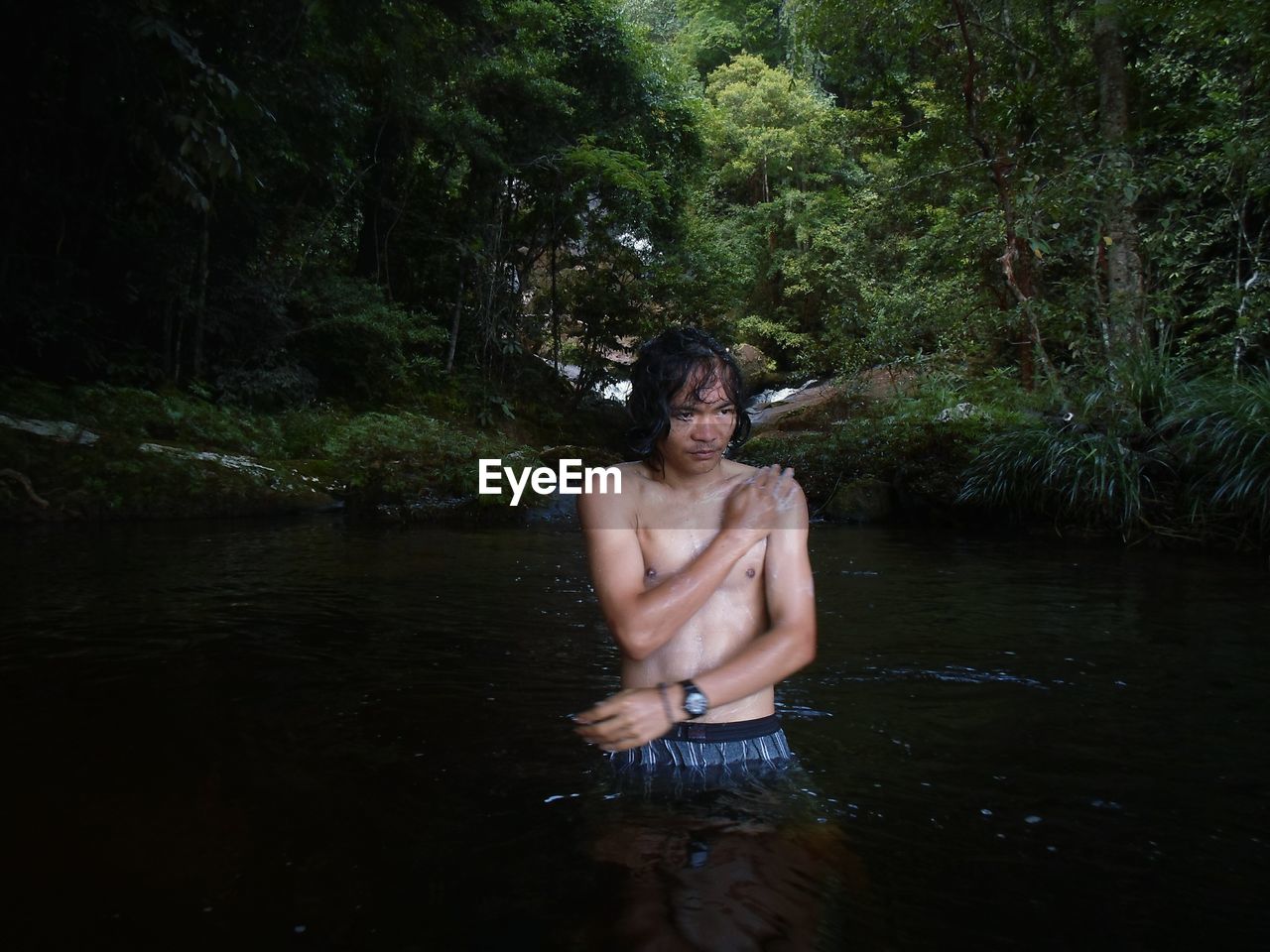 Shirtless man bathing in river at forest