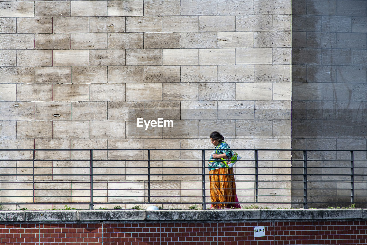 REAR VIEW OF CHILD STANDING ON WALL