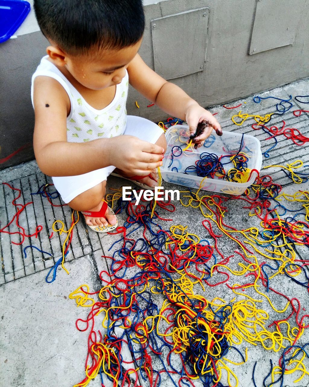 High angle view of boy collecting colorful threads on footpath