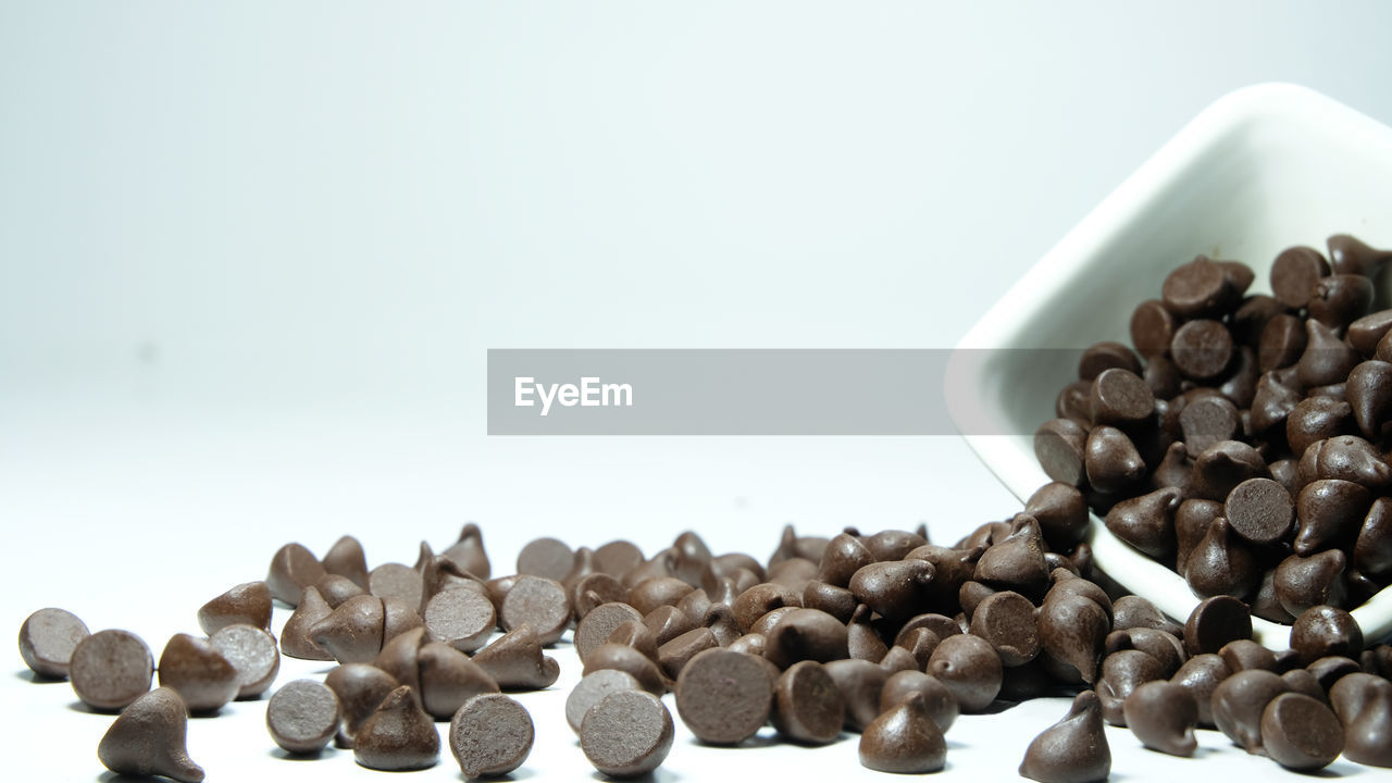 Many chocolate chips are on gray abstract background. slices of chocolate sweet food photo concept