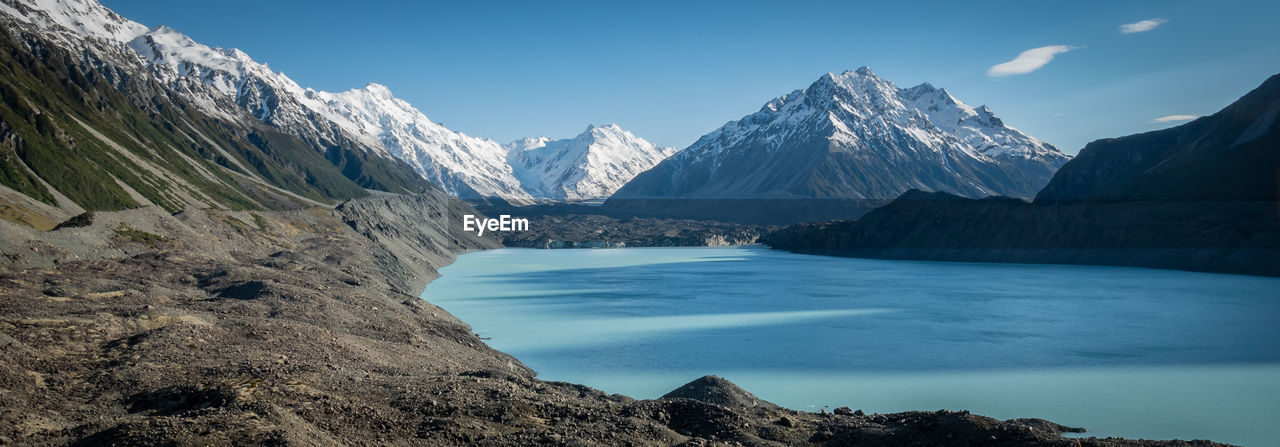 Panoramic shot of blue glacial lake and glacier with mountains in backdrop.mt cook np, new zealand