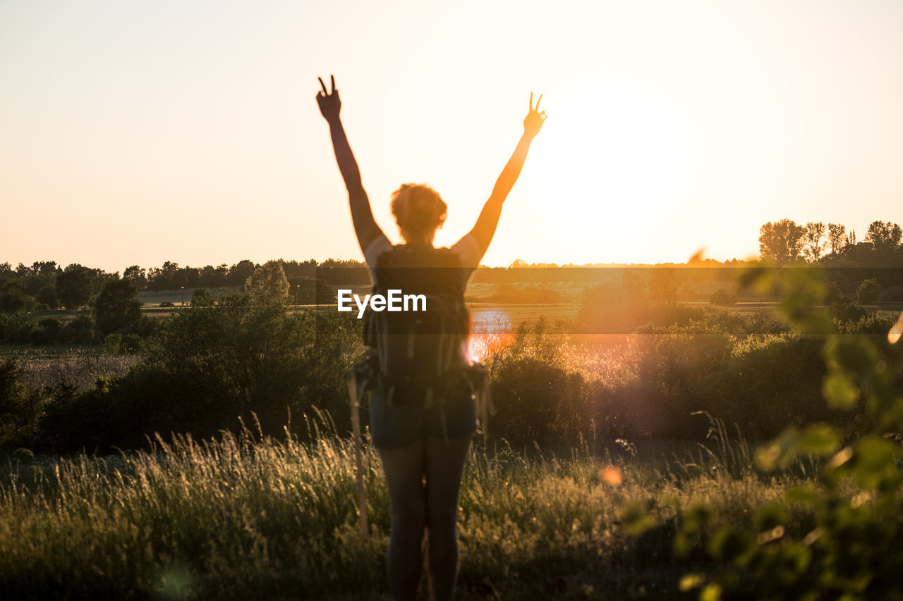 Rear view of woman standing on field against sky