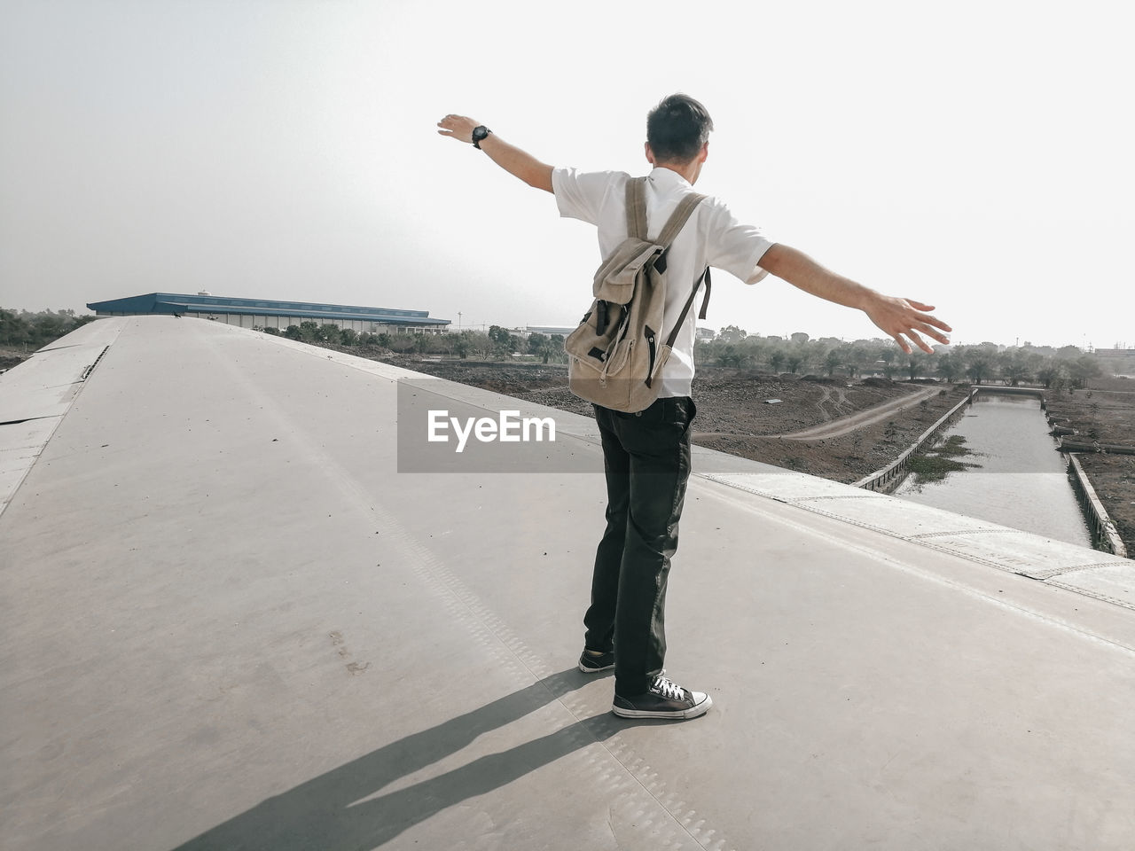 MAN STANDING ON ROAD AGAINST CLEAR SKY