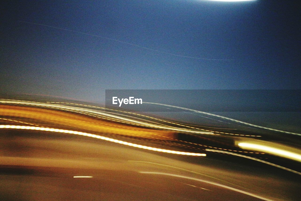 Light trails on road against clear sky at night