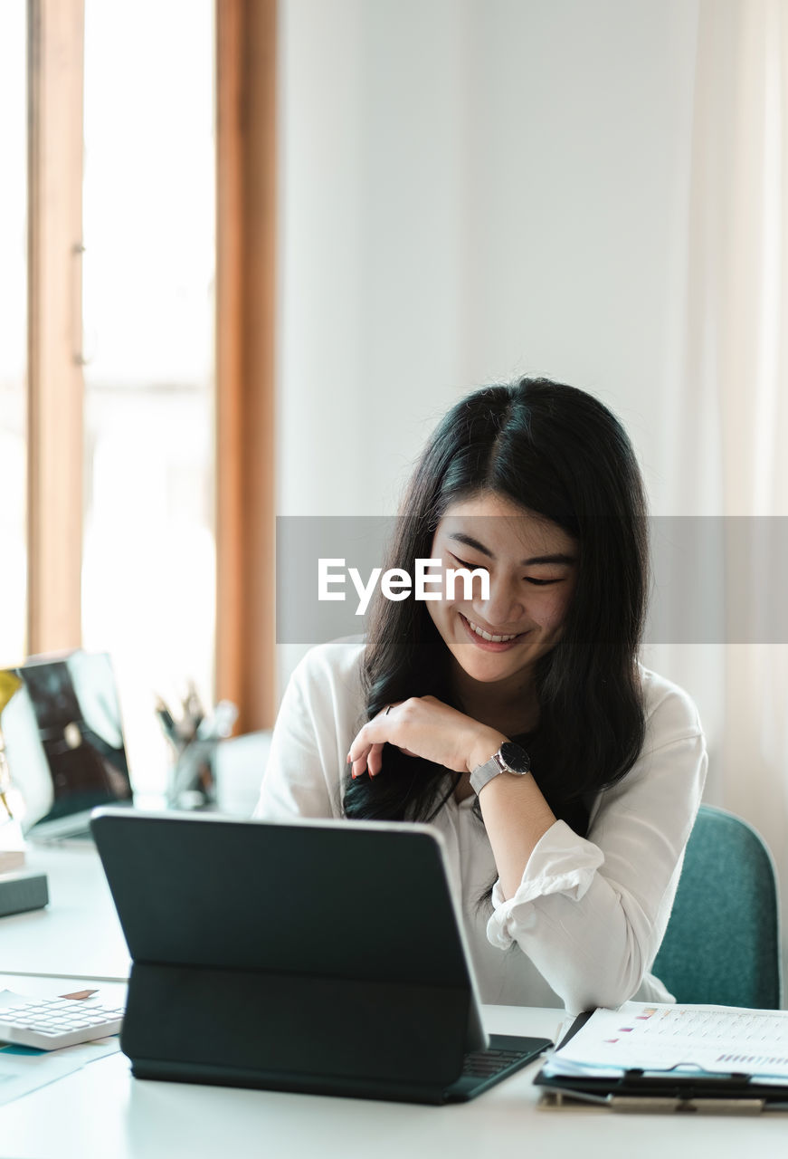 Smiling businesswoman using laptop at office