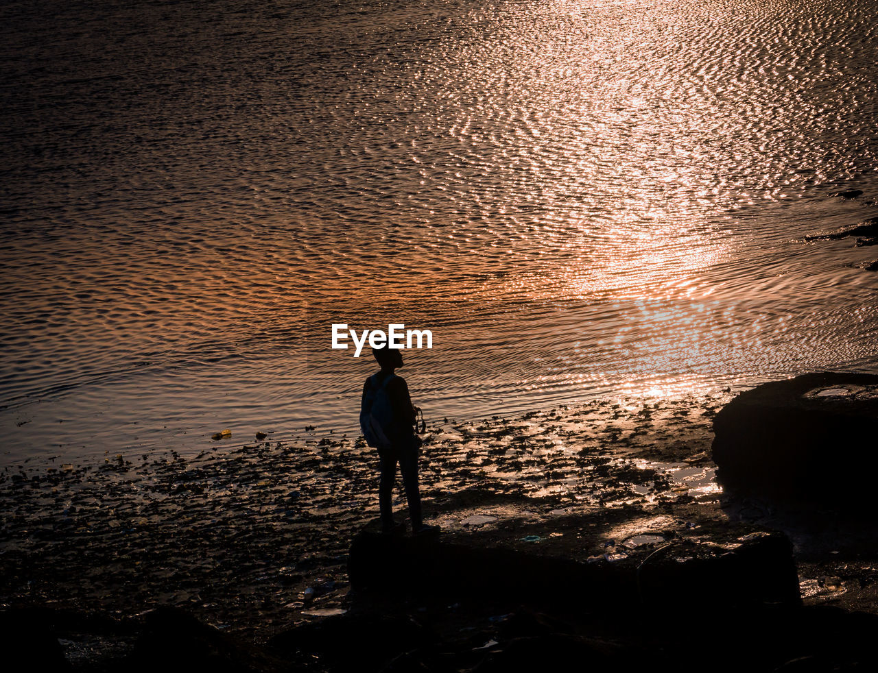 SILHOUETTE MAN STANDING AT BEACH AGAINST SKY DURING SUNSET