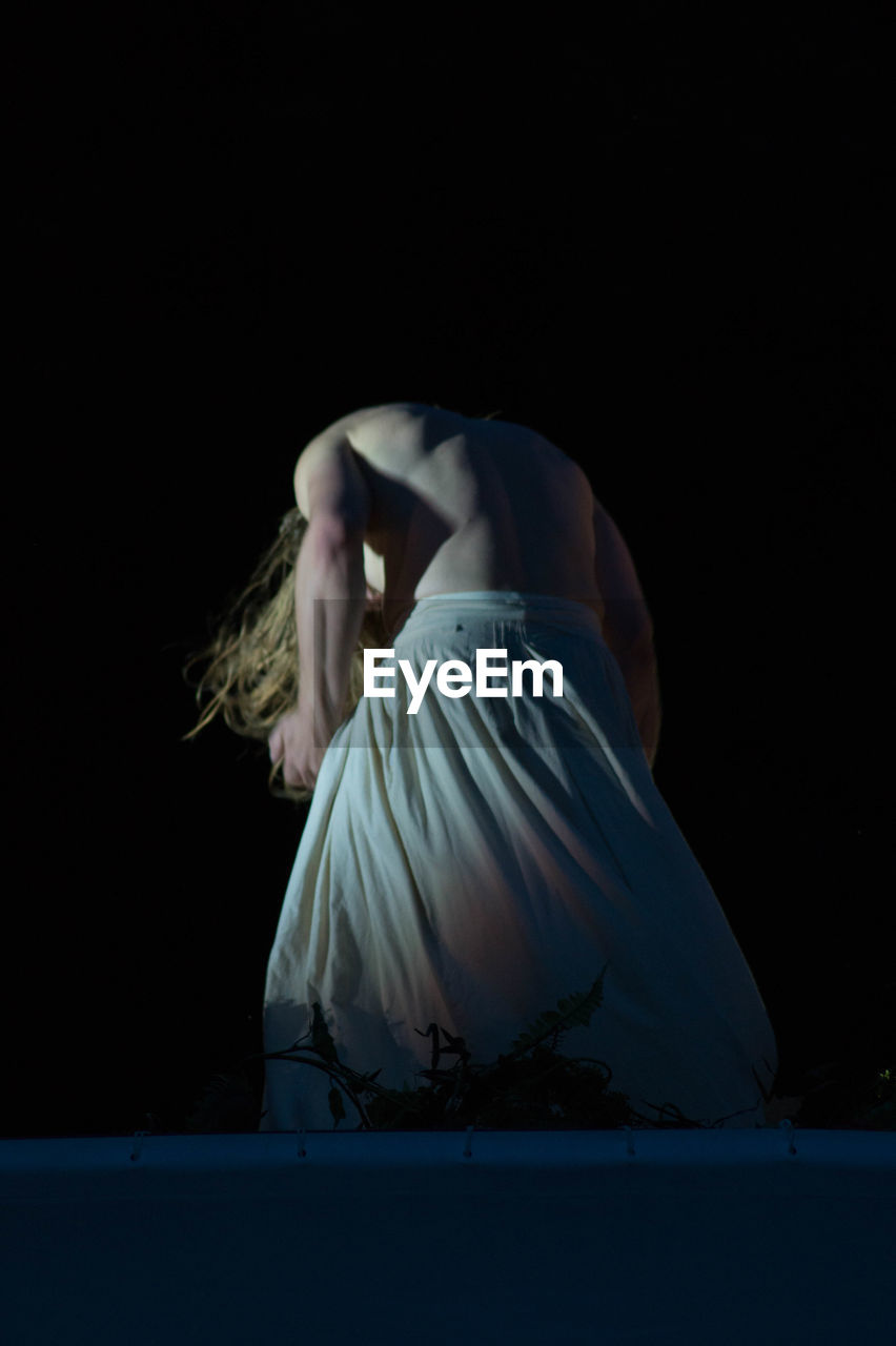 YOUNG WOMAN WEARING MASK AGAINST BLACK BACKGROUND