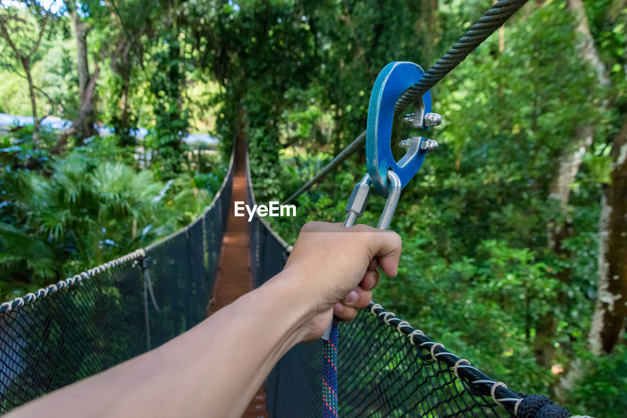 Cropped image of man hiking on footbridge in forest