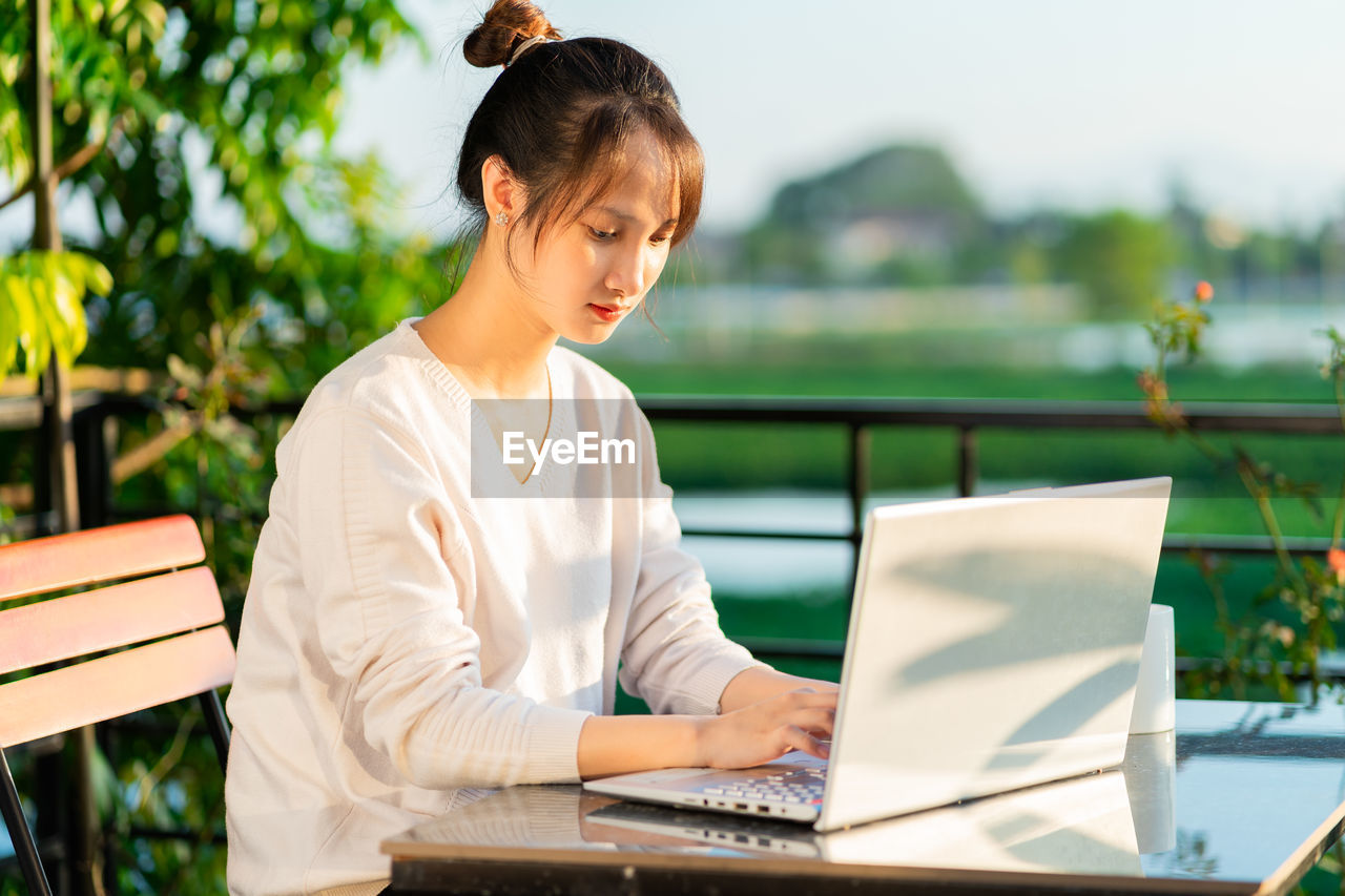 young woman using laptop while sitting on table
