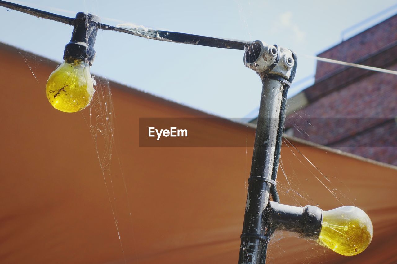 Low angle view of spider web on yellow light bulbs