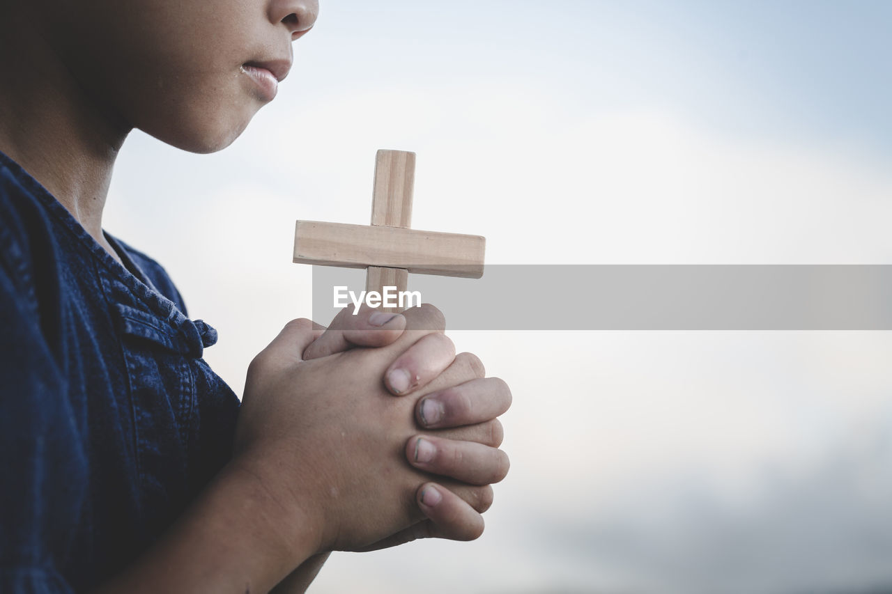 CLOSE-UP OF MAN HOLDING CROSS AGAINST BLURRED MOTION