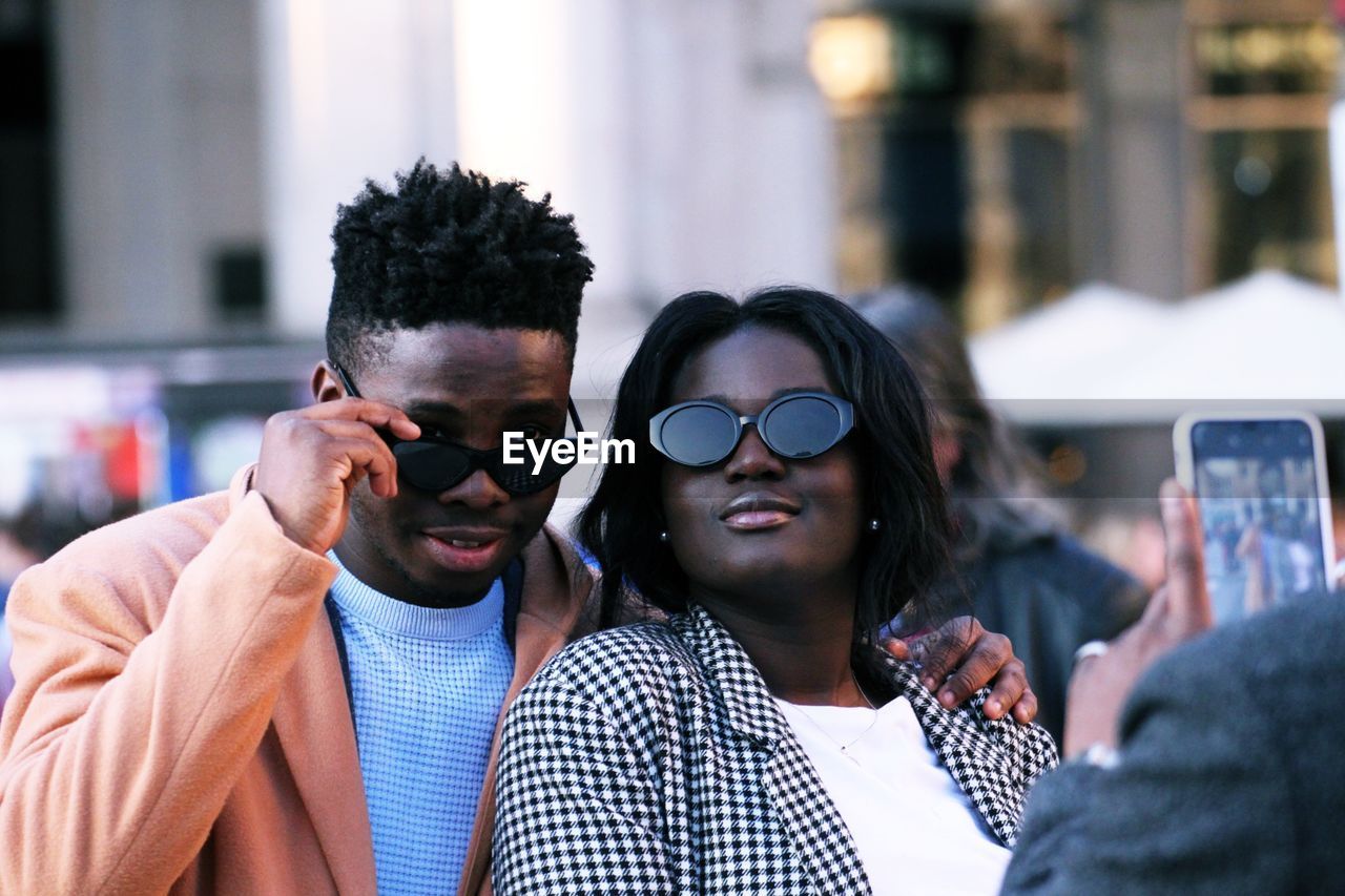 Friend photographing young couple in city 