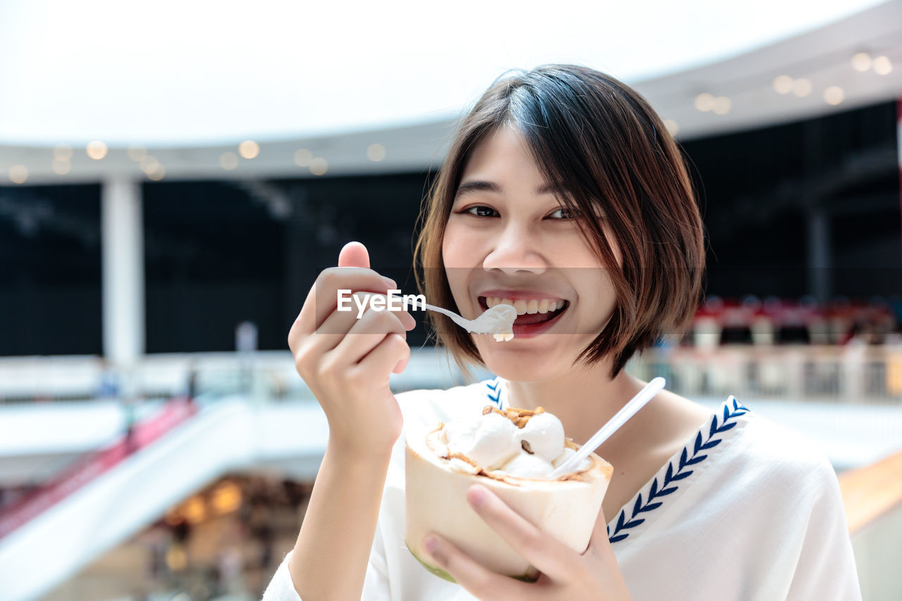 Coconut ice cream in coconut shell in woman hands enjoying eating, thailand street food