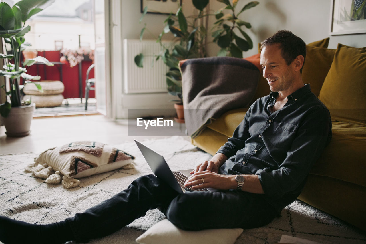 Smiling businessman working on laptop in living room