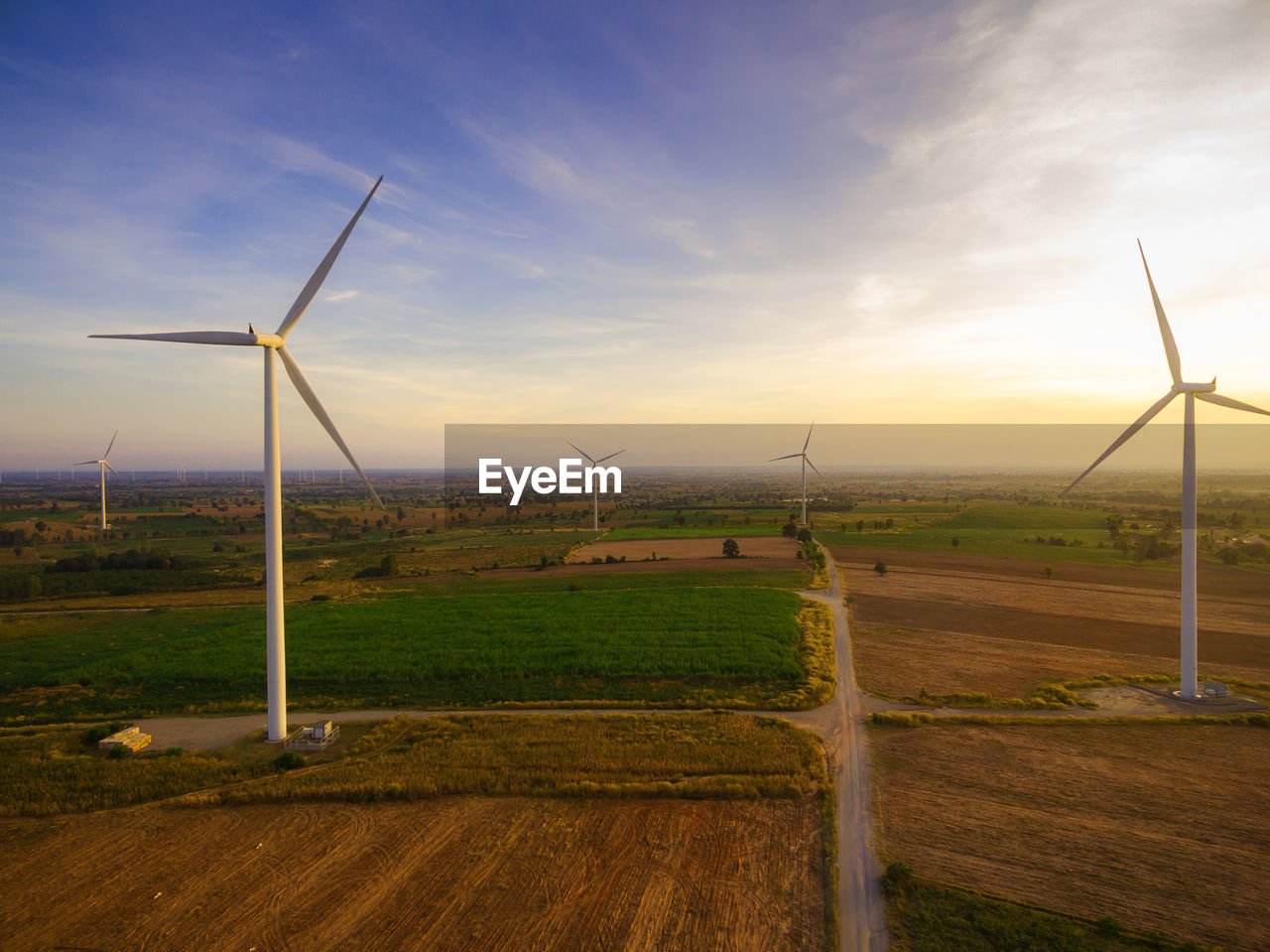 Windmills on landscape against sky during sunset