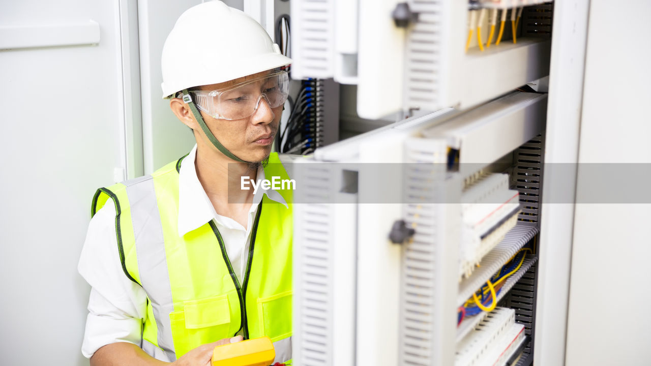 Electrician engineer work tester measuring voltage of power electric line