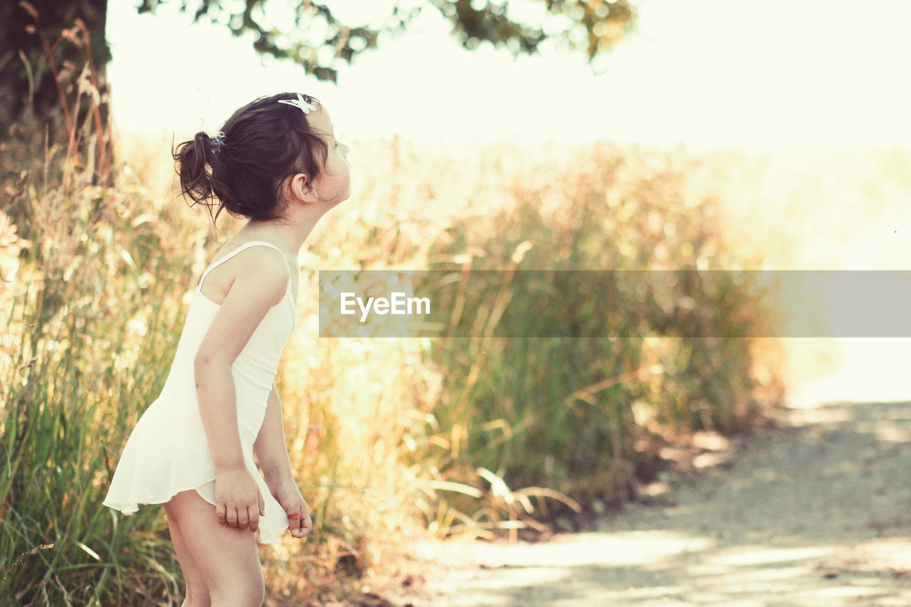 Side view of girl standing by plants