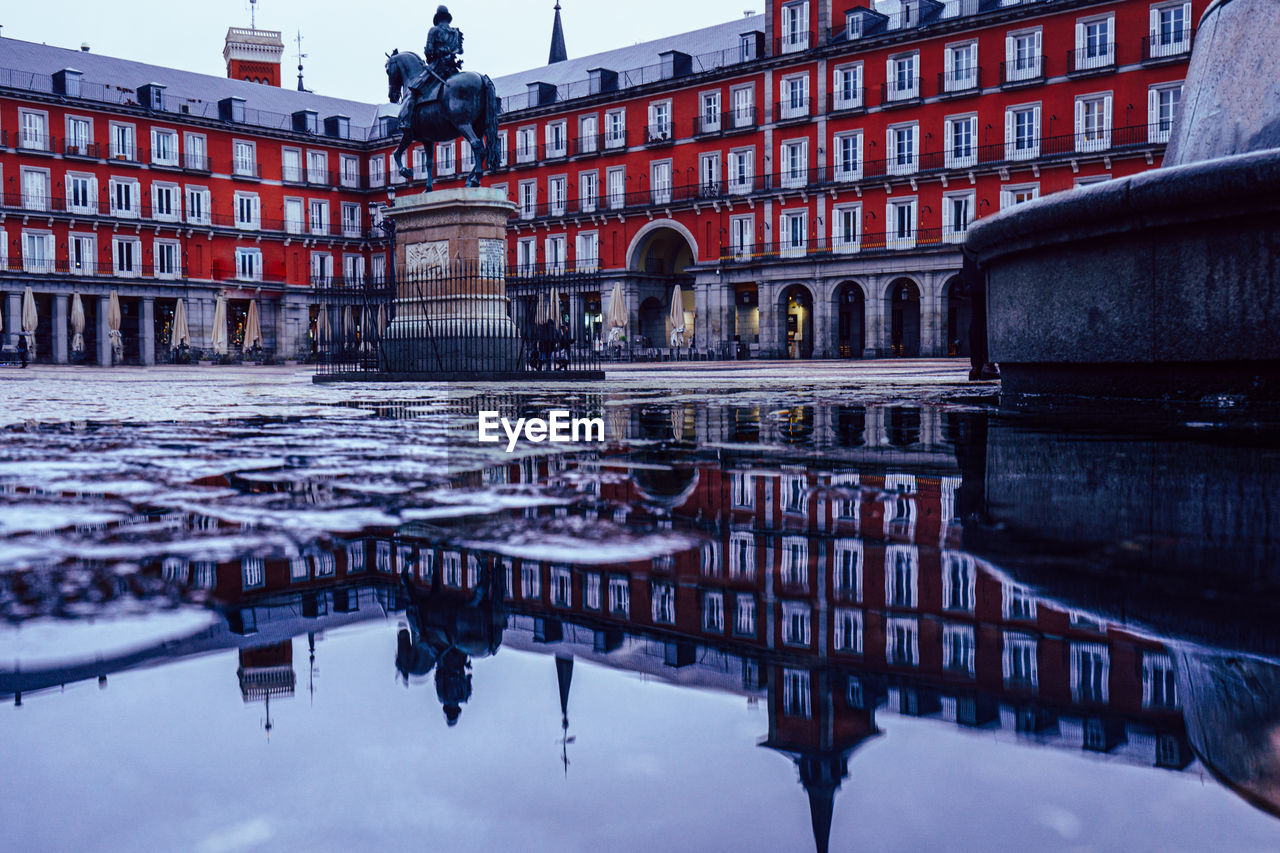 REFLECTION OF BUILDINGS IN PUDDLE ON CANAL IN CITY