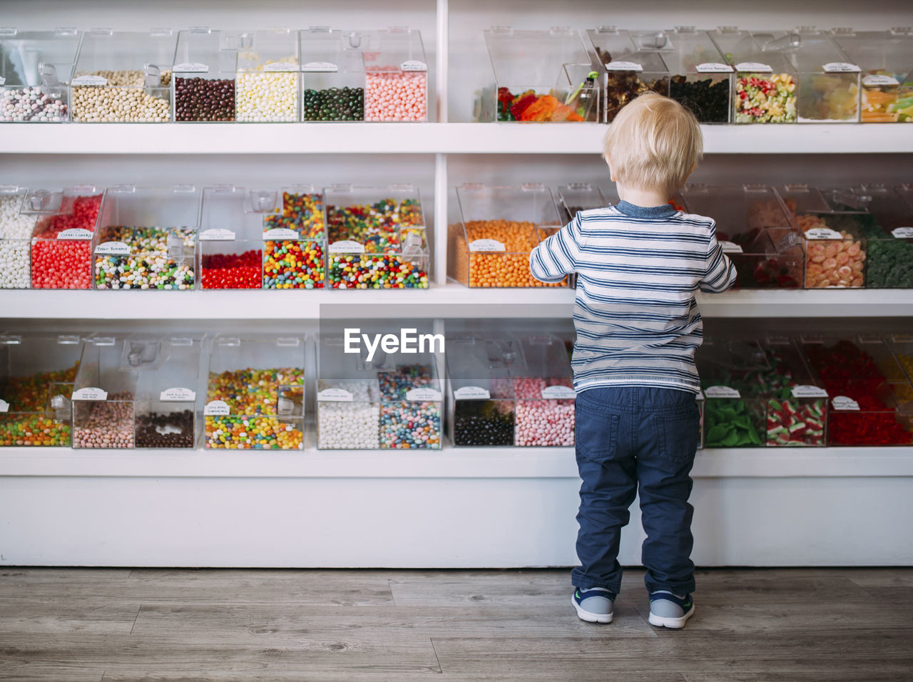 Rear view of boy standing against shelves in store