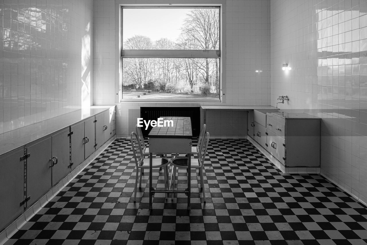 Empty chairs and tables in tiled floor in a modern french 1920's villa.