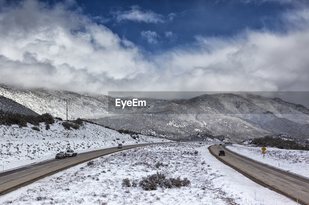 Snow covered road by mountain against sky