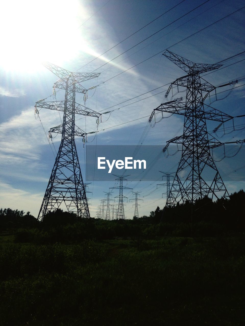 Electricity pylons against wispy cloud