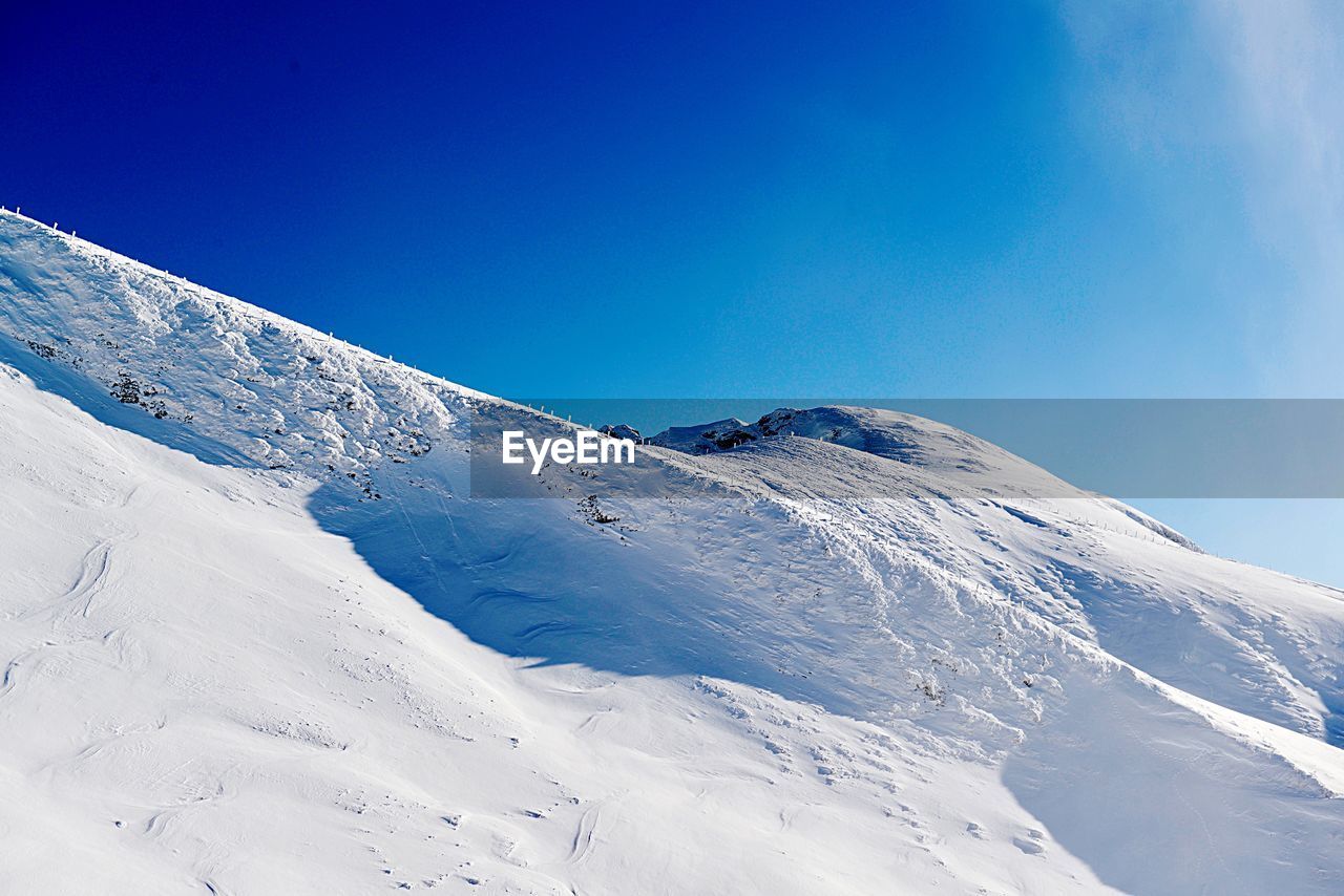 Snow covered mountain against blue sky