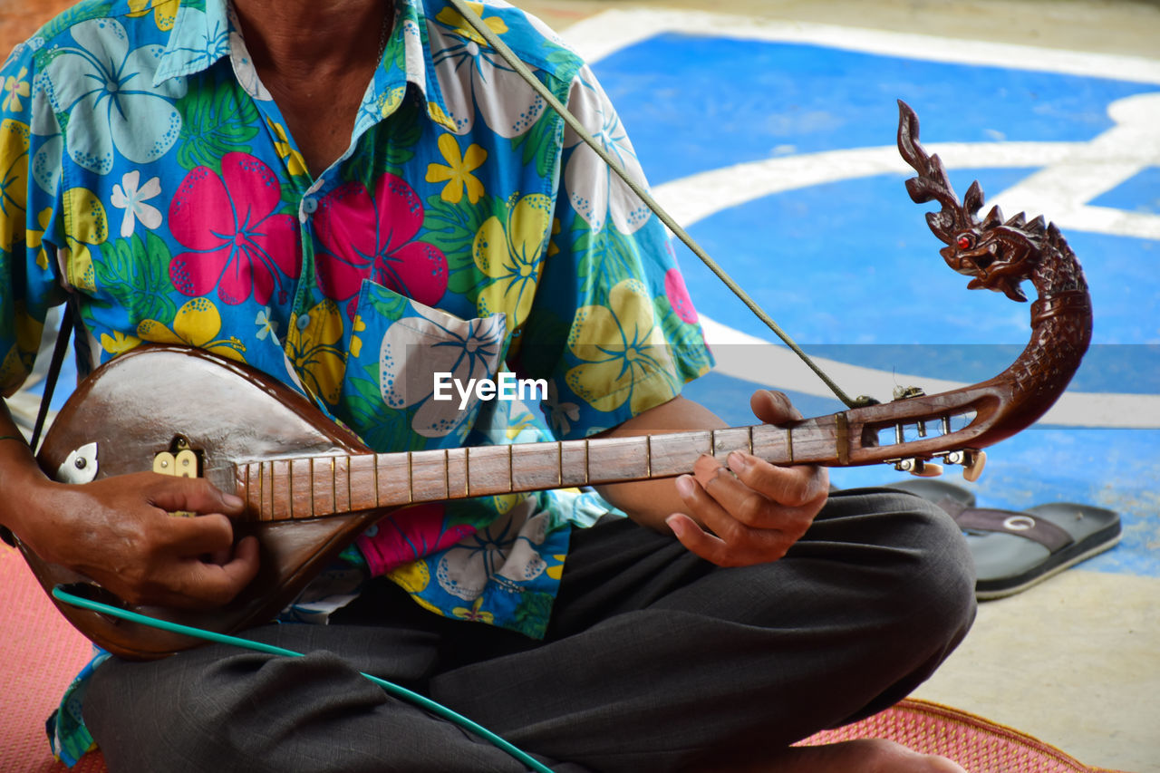 Midsection of man playing guitar