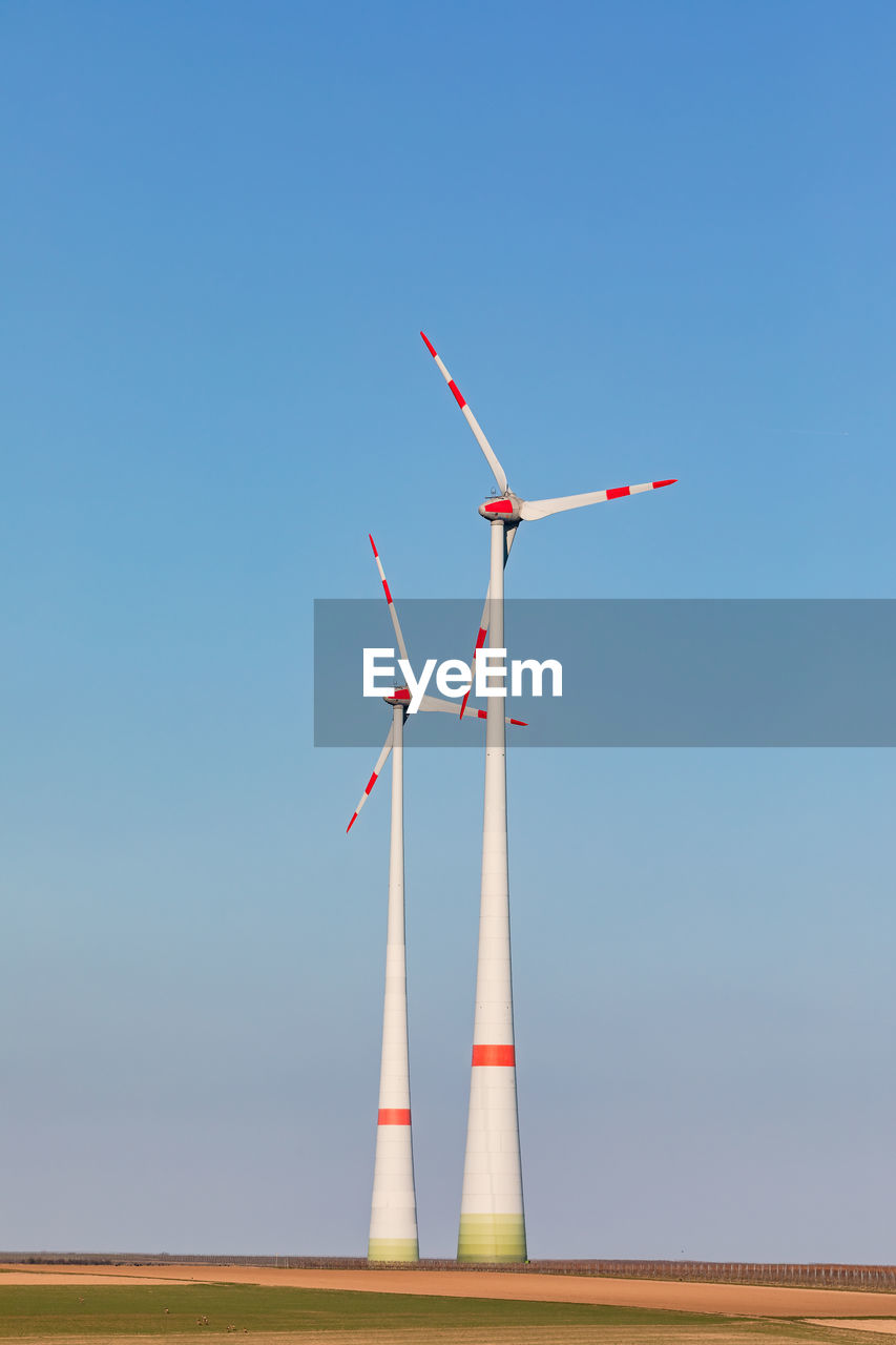 Two wind turbines dominate nature in rural germany against clear sky