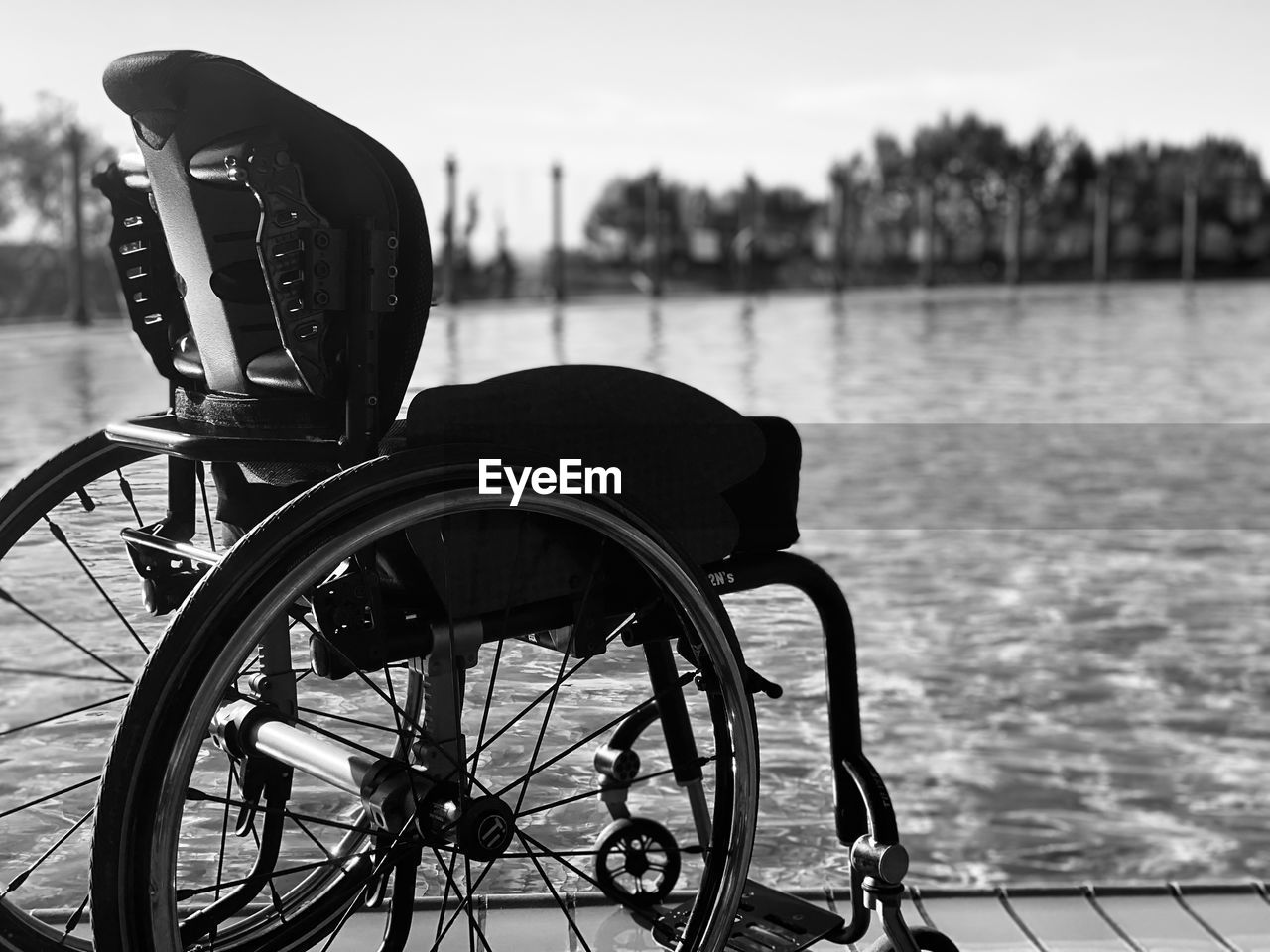 Close-up of bicycle wheel by lake against sky