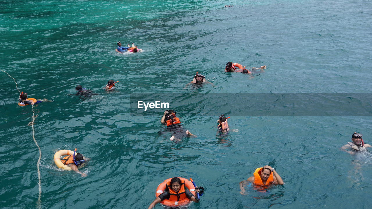 HIGH ANGLE VIEW OF PEOPLE FLOATING ON SEA