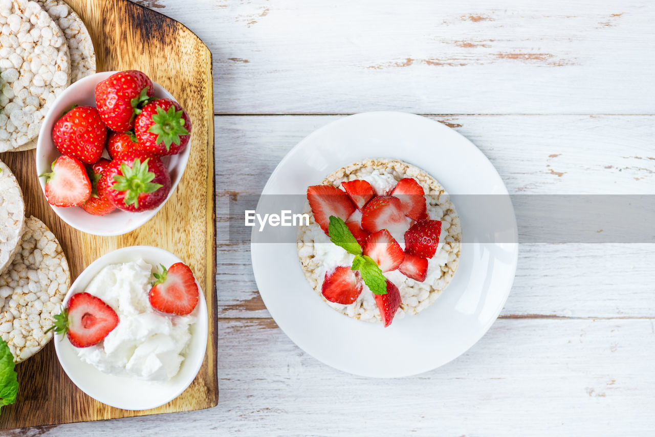 Healthy snack from rice cakes with ricotta and strawberries on light wooden background