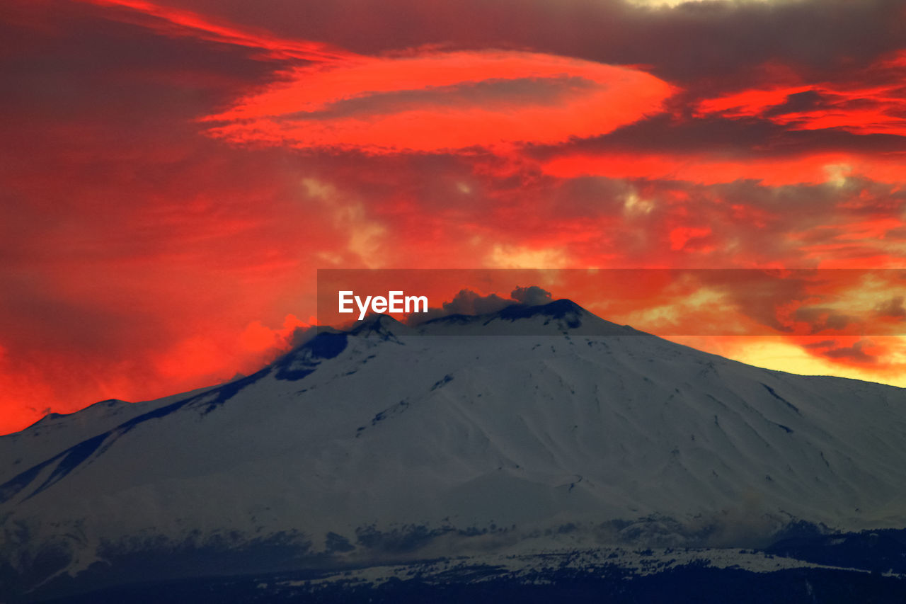 Scenic view of snowcapped mountain against cloudy sky during sunset